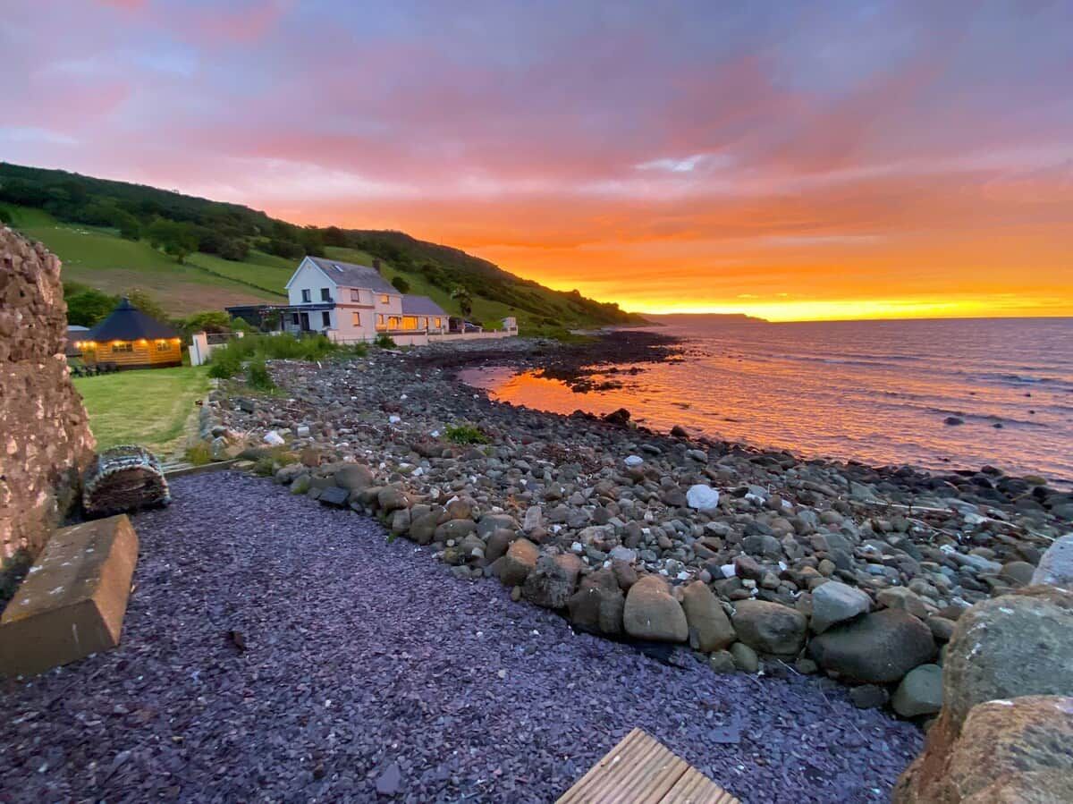 A coastal property with a stone wall, a wooden deck, and a view of the sea.