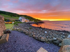 A coastal property with a stone wall, a wooden deck, and a view of the sea.
