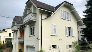 Une maison à deux étages avec un garage, un balcon et un petit jardin.