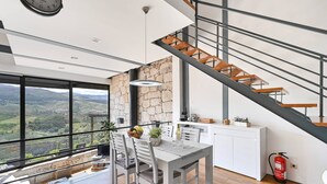 Une cuisine moderne avec un mur en pierre, un coin repas offrant une vue agréable et un escalier.