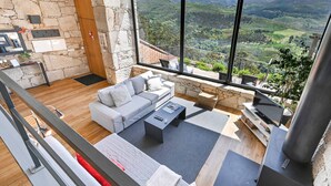 Un salon moderne avec un mur en pierre, un canapé, une table basse et un téléviseur.