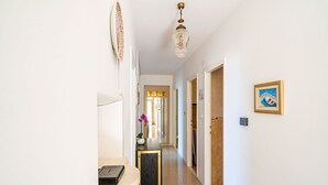 A hallway with a desk, a vase with flowers, and a framed picture on the wall.