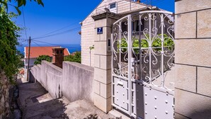 A narrow street with a gated entrance, a building with a sign '7', and a clear blue sky.