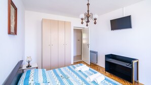 A bedroom with a bed, a TV, a wardrobe, and a chandelier.