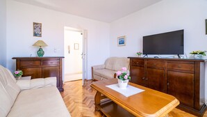 A living room with a sofa, a wooden coffee table, a television, and a cabinet.