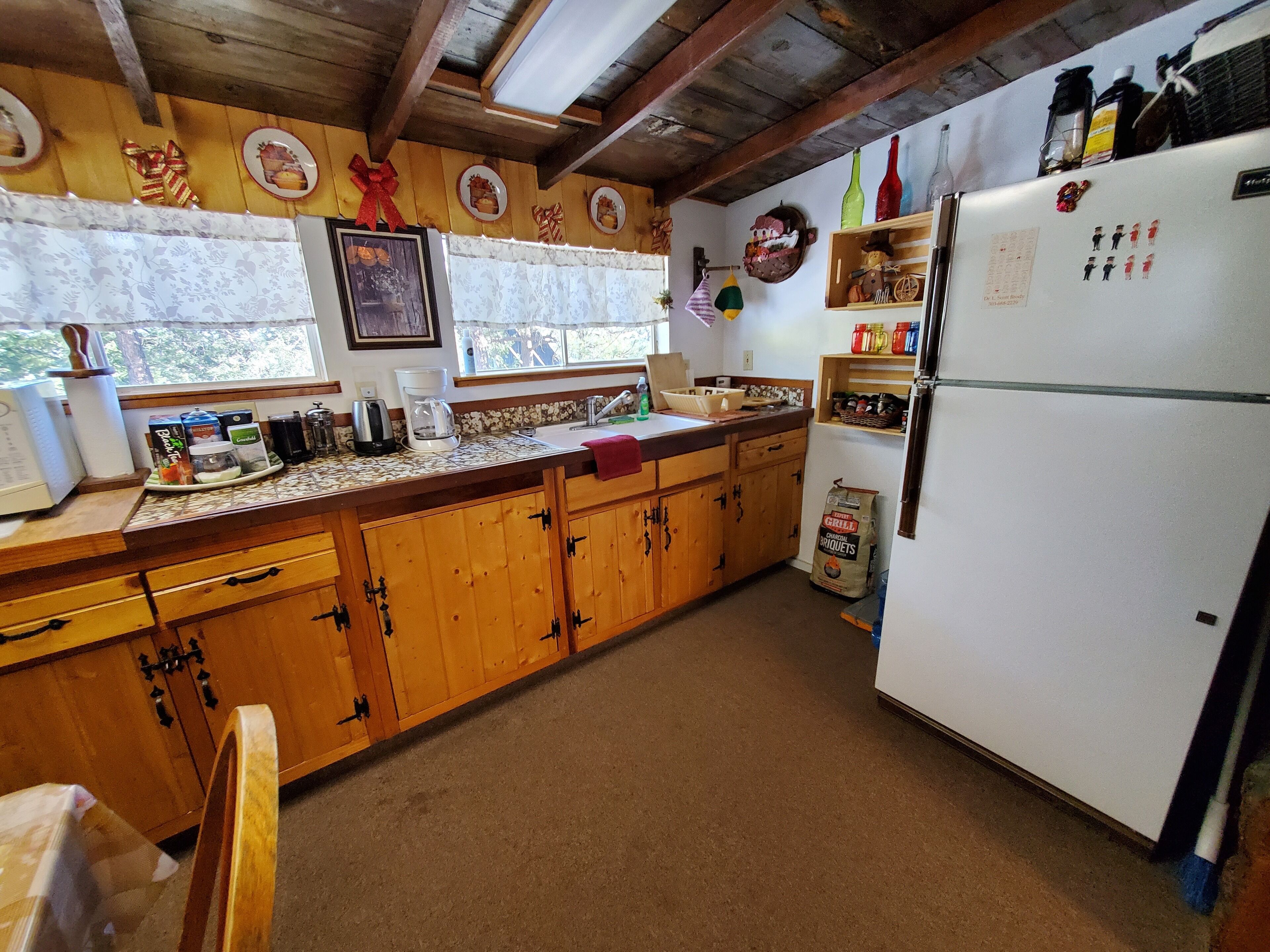 A rustic kitchen with wooden cabinets, a white refrigerator, and various kitchen appliances.