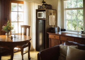Una cocina acogedora con una mesa de madera, sillas, un refrigerador y una ventana con vistas a zonas verdes.