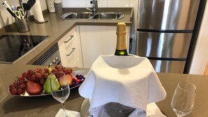 Un plan de travail de cuisine avec une assiette de fruits, une bouteille de champagne et deux verres à vin.