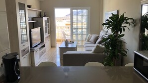 Un salon moderne avec un téléviseur, un canapé et un balcon offrant une vue agréable.