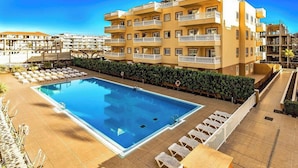Un hôtel doté d’une piscine, de plusieurs balcons et d’un jardin bien entretenu.