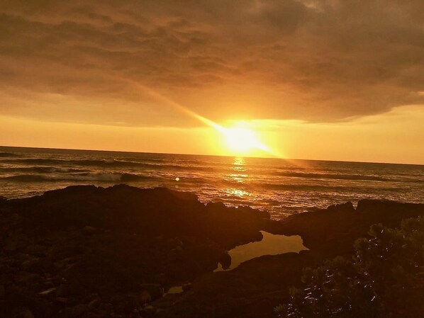 Ein Sonnenuntergang über dem Meer mit einer felsigen Küste.