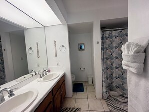 Ein Badezimmer mit zwei Waschbecken, einem Spiegel, einer Duschvorhang mit einem Seesternmuster und einem Handtuchhalter.