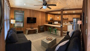 A cozy cabin interior with a living room, kitchen, and dining area.