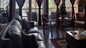 Un salón espacioso con ventanas amplias, un sofá de cuero, una mesita y un árbol de Navidad.
