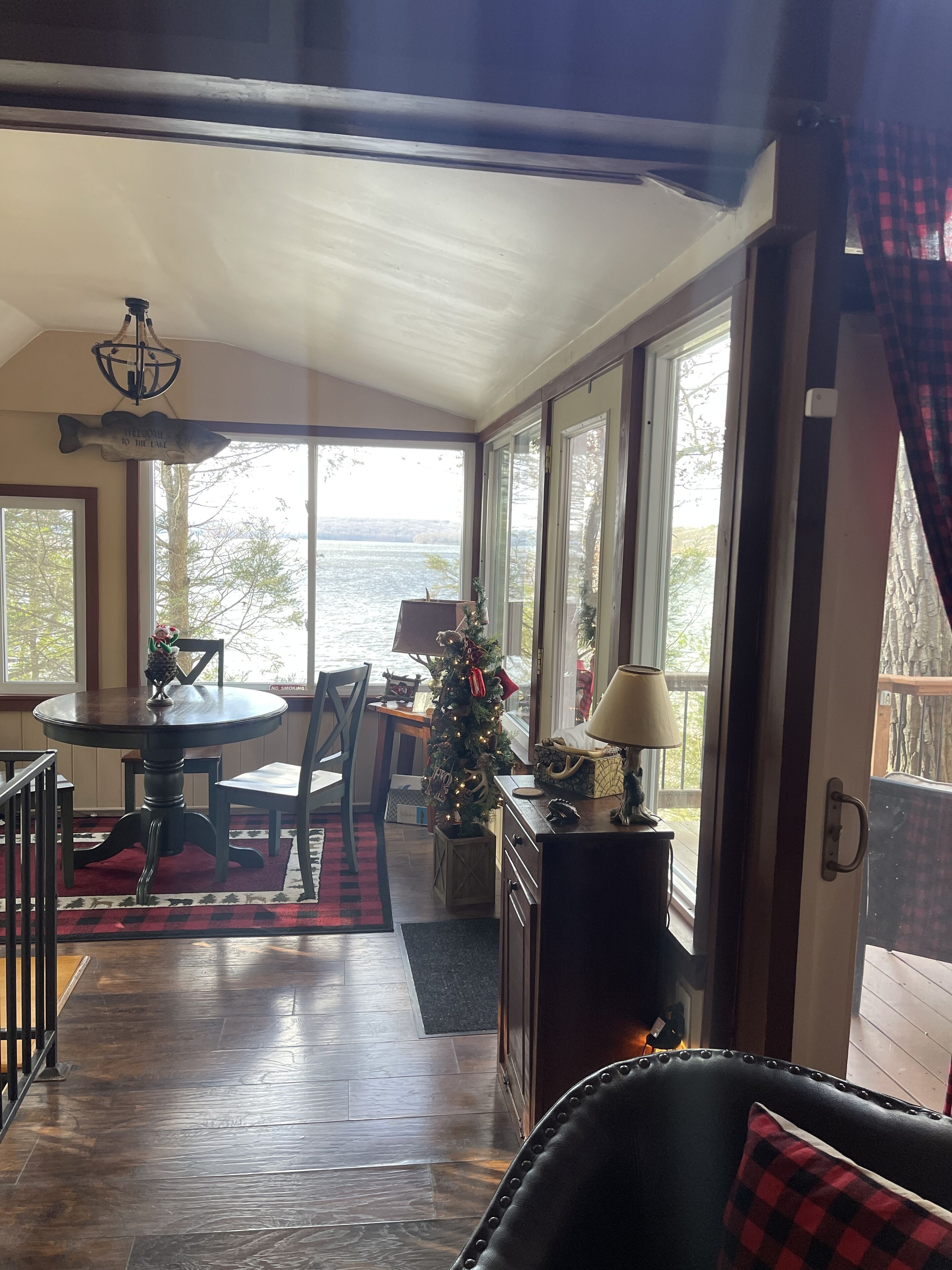 Un coin repas chaleureux avec une table et des chaises, un sapin de Noël et une vue sur le lac.