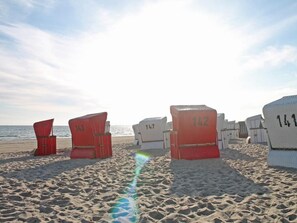 Strandkörbe mit den Nummern 143, 142 und 147 an einem Sandstrand mit Blick auf das Meer.