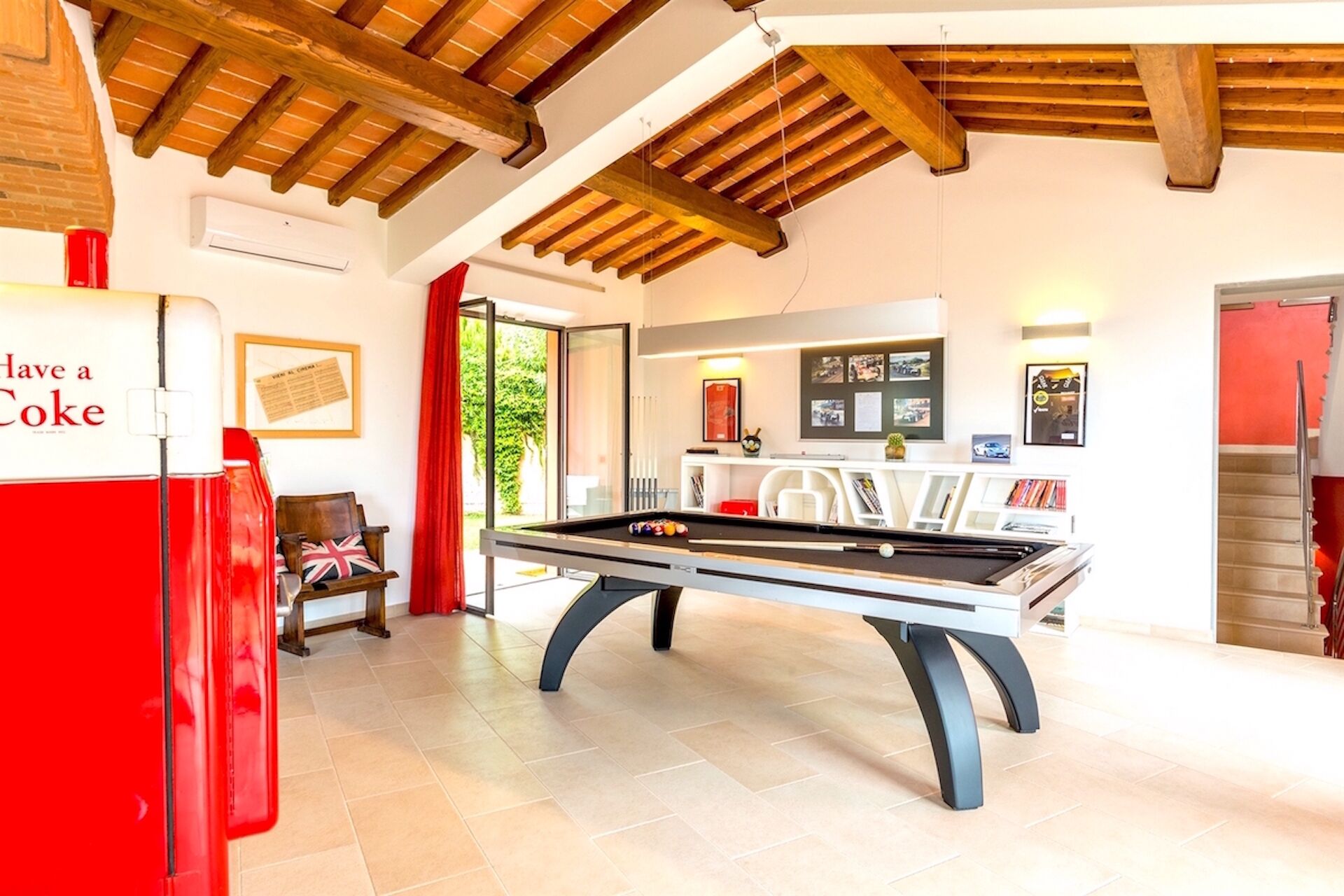 Une table de billard dans une pièce dotée d’un plafond haut et de poutres apparentes.
