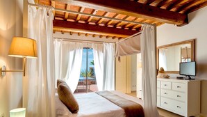 Un dormitorio con cama a dosel, una lámpara de noche, un televisor y vistas al exterior.