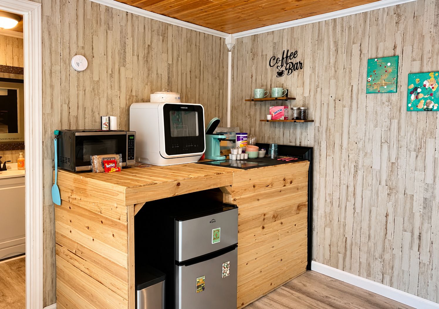 Una cocina con encimera de madera, microondas, refrigerador y un letrero que dice 'Coffee Bar'.