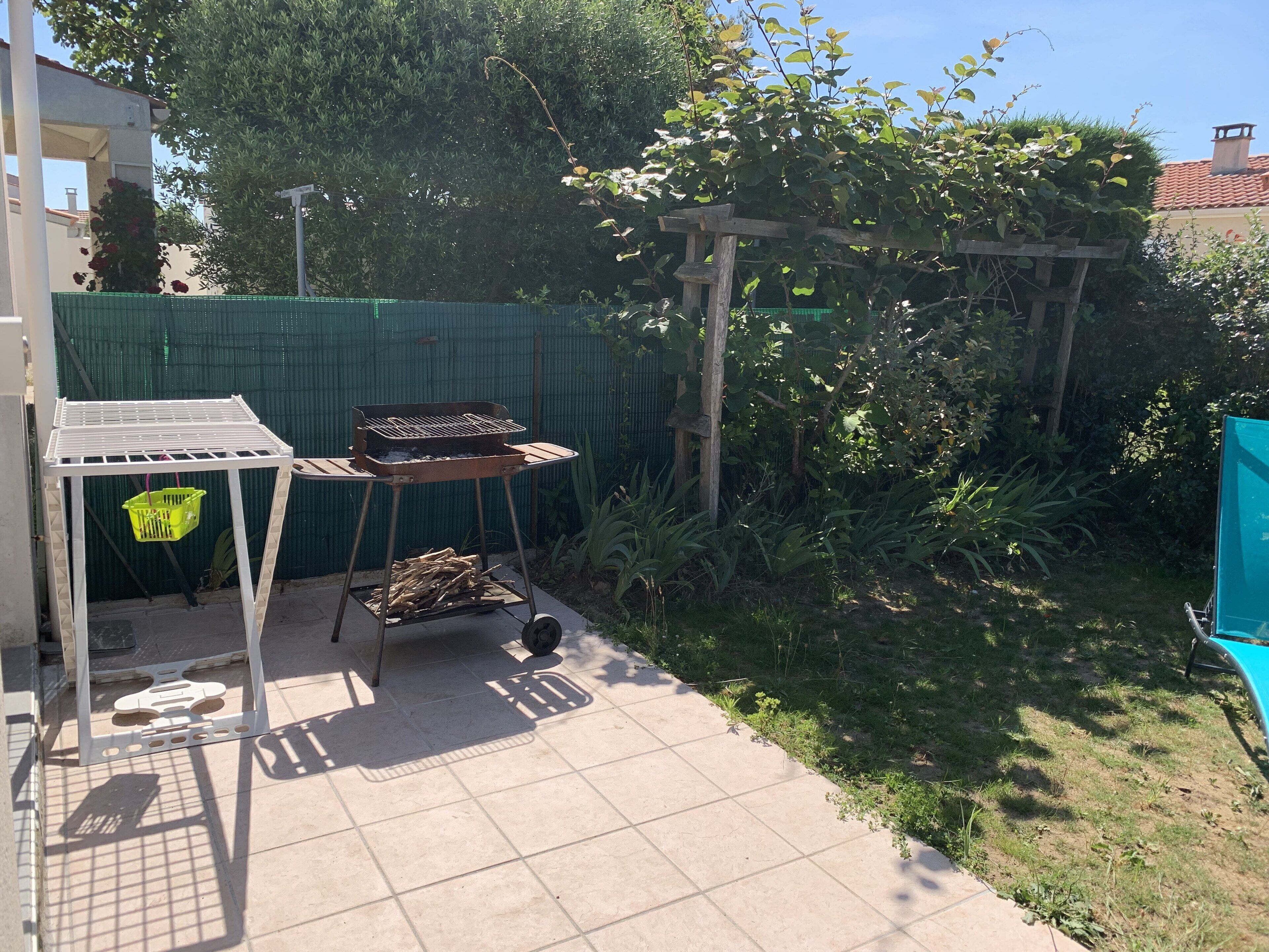 A patio area with a grill, a table, and a green basket.