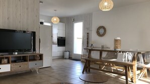 A modern living room with a TV, wooden furniture, and a dining area with a table and chairs. - Renovated house, 300m from the beach, with a boule court (La Brée-les-Bains)