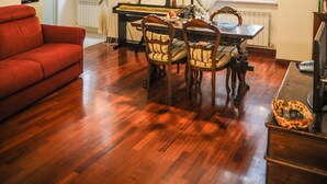 Una sala de estar acogedora con techo de madera, una mesa de comedor con sillas, un sofá rojo y una ventana con cortinas.