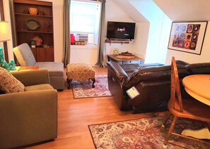 Relax in this inviting living room with a flat-screen TV, plush armchair, and comfortable sofa.