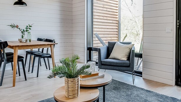 Un intérieur moderne avec une table à manger en bois, des chaises noires, une table basse ronde et un canapé gris.