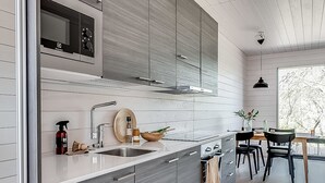 Une cuisine moderne avec des meubles de couleur grise, un évier en acier inoxydable et un coin repas comprenant une table et des chaises en bois.