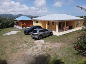 A two-story house with a covered patio and a car parked in front. - FULL HOUSE IN BEAUREGARD (Le François)