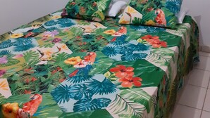 Een bed met een bloemenprint, twee kussens en een raam met luiken.