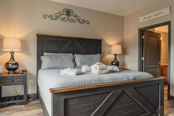 A bedroom with a dark wooden bed frame, two bedside tables with lamps, and a decorative wall piece above the bed.