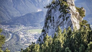 A mountainous landscape with a prominent rocky peak in the foreground, a valley with buildings, and distant mountain ranges under a clear sky. - Fewo Ideale Lage Wohn/Schlafzimmer Bad /WC Terrasse (Bad Reichenhall)