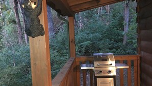 Una terraza de madera con una parrilla y una escultura de oso.