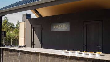 A modern outdoor bar area with a sign reading "AMADOURO SKY BAR" and bowls of snacks on a counter.