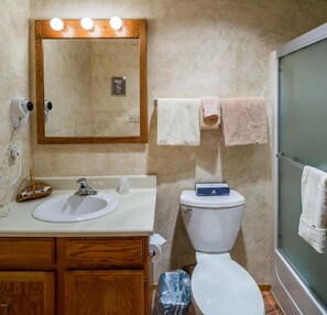 Une salle de bain avec un meuble-lavabo en bois, un miroir avec éclairage intégré, des toilettes et un porte-serviettes.