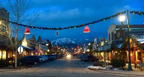 Une rue bordée d’immeubles, illuminée de guirlandes lumineuses, avec une montagne en arrière-plan.