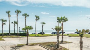 A parking lot with palm trees and a view of the ocean.