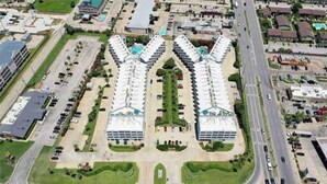 A large hotel with a central courtyard, multiple parking lots, and a main road in the background.