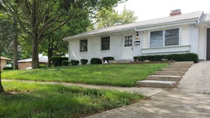 A white two-story house with a front yard, a driveway, and a set of concrete steps leading to the front door. - MOTELS ARE GROSS
BEAUTIFUL RANCH STYLE
Approx 145 Nightly

DISCOUNTS AVAILABLE 
 (Columbus)