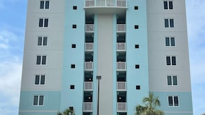 Un hotel de varios pisos con un atrio central, estacionamiento y varios vehículos.