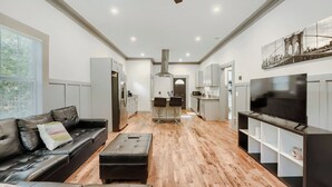 A modern living room with a sofa, ottoman, and a TV on a stand.