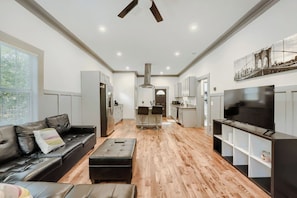 A modern living room with a sofa, ottoman, and a TV on a stand.