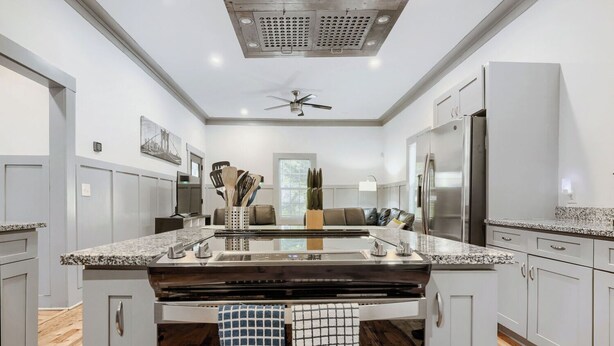 A modern kitchen with a central island, stainless steel appliances, and a ceiling fan.