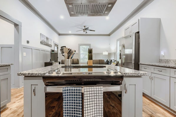 A modern kitchen with a central island, stainless steel appliances, and a ceiling fan.