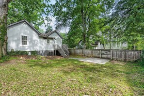 A residential property with a wooden deck, a fenced backyard, and a house with a porch.
