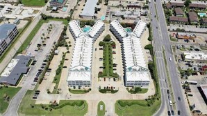 Et stort hotel med en central gårdsplads, flere parkeringspladser og en hovedvej i baggrunden.
