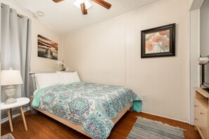 A bedroom with a bed, a nightstand, a lamp, a painting, and a dresser. - Casa Riviera Beachfront Condo-Great View, Two Pools (Galveston)