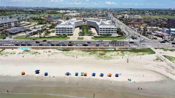 Et kysthotel med udsigt over stranden, flere etager og parkeringsplads.