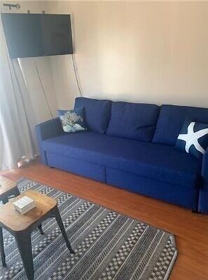 A living room with a blue sofa, a small wooden table, and a patterned rug. - Casa Riviera Beachfront Condo-Great View, Two Pools (Galveston)